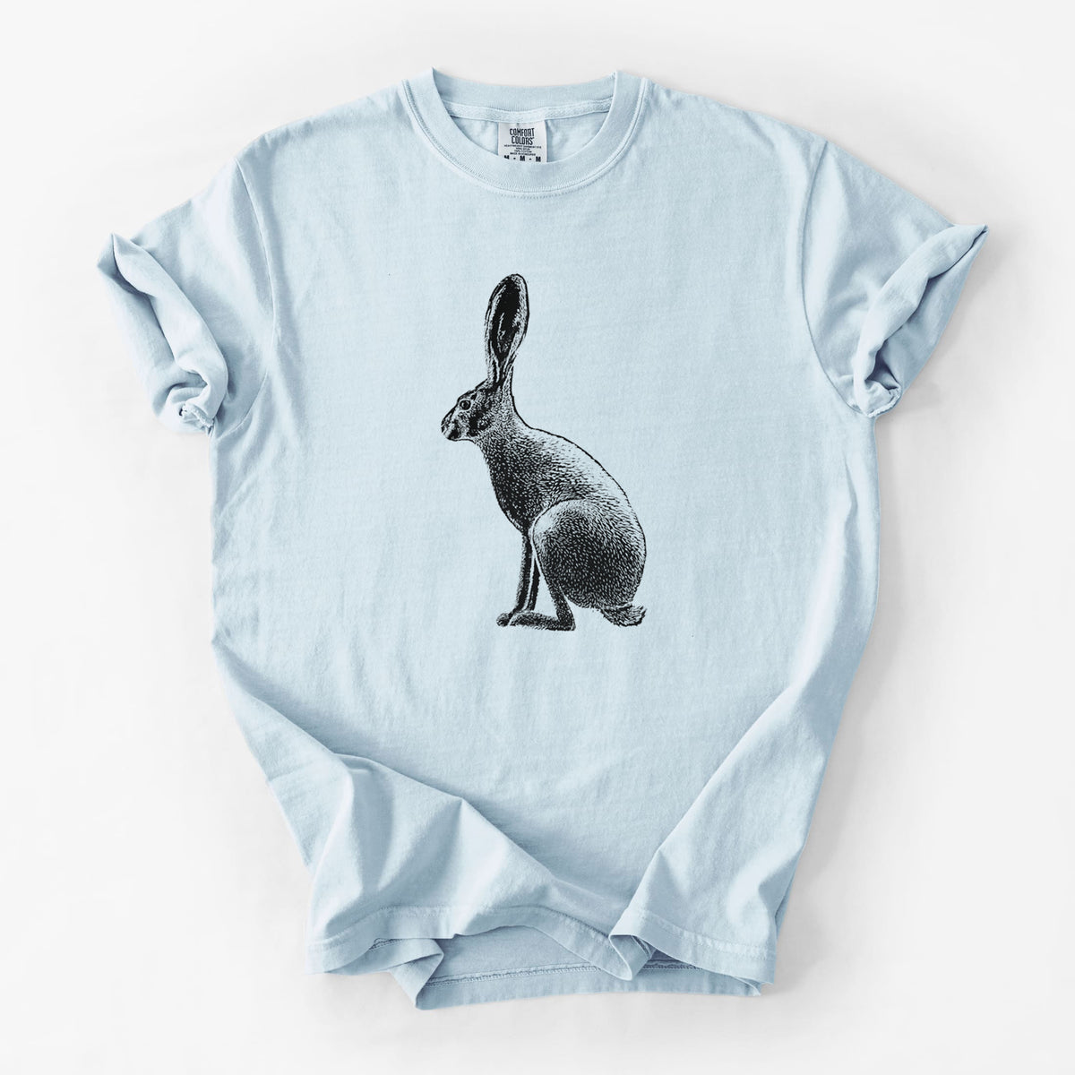 Chambray blue Comfort Colors t-shirt laid flat, printed with a detailed black ink illustration of a black-tailed jackrabbit sitting in profile with tall ears.