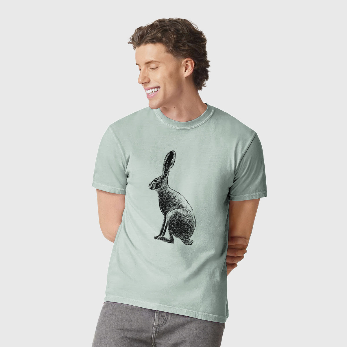 Man wearing a Comfort Colors t-shirt printed with a detailed black ink illustration of a black-tailed jackrabbit sitting in profile with tall ears.