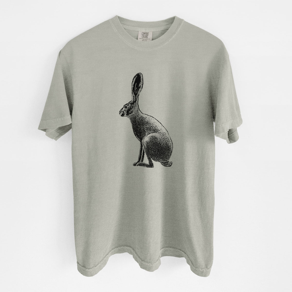 Sandstone beige Comfort Colors t-shirt laid flat, printed with a detailed black ink illustration of a black-tailed jackrabbit sitting in profile with tall ears.