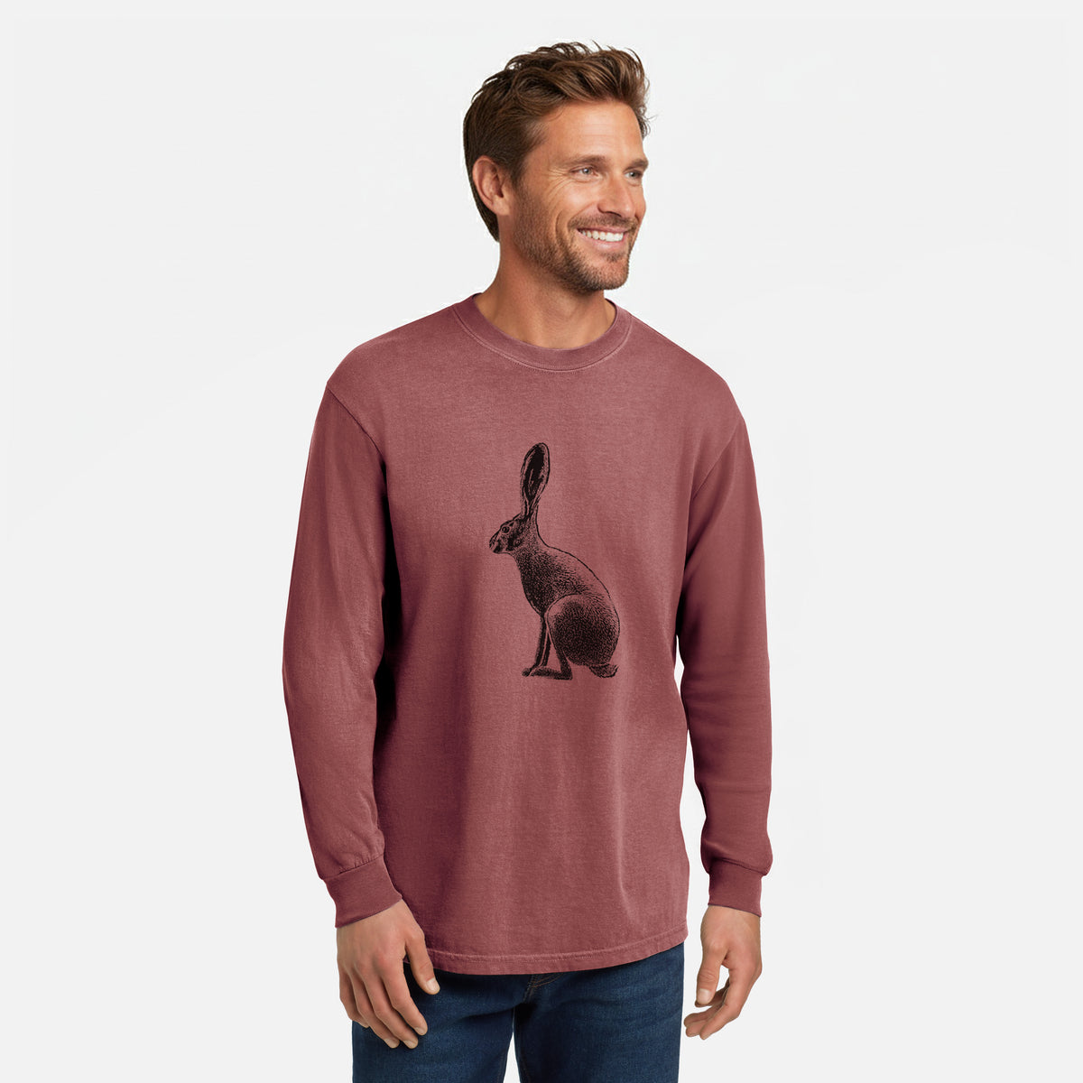 Brick red Comfort Colors long sleeve shirt printed with a detailed black ink illustration of a black-tailed jackrabbit sitting in profile with tall ears, shown in a lifestyle photo.