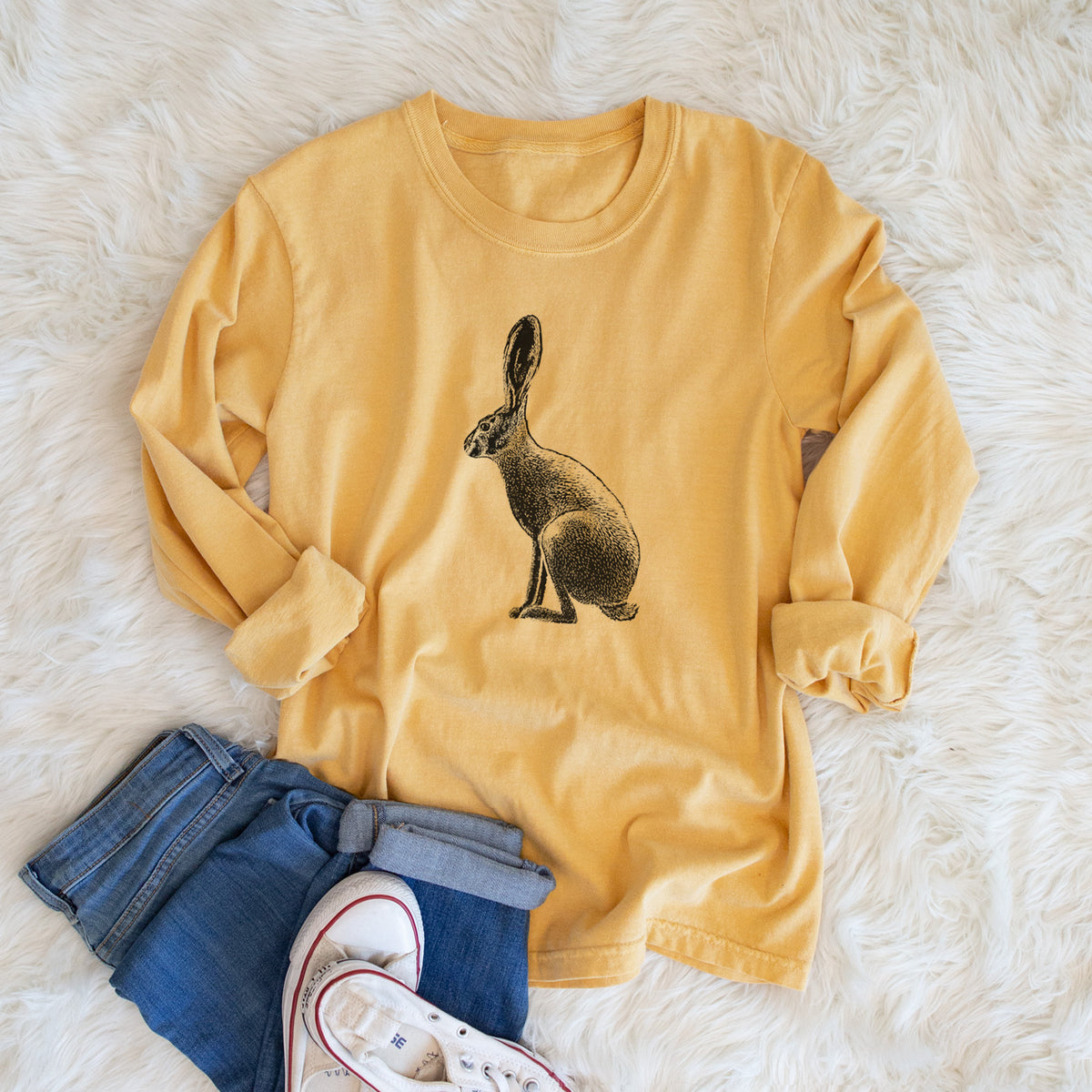 Golden wheat yellow Comfort Colors long sleeve shirt printed with a detailed black ink illustration of a black-tailed jackrabbit sitting in profile with tall ears, shown in a lifestyle photo.