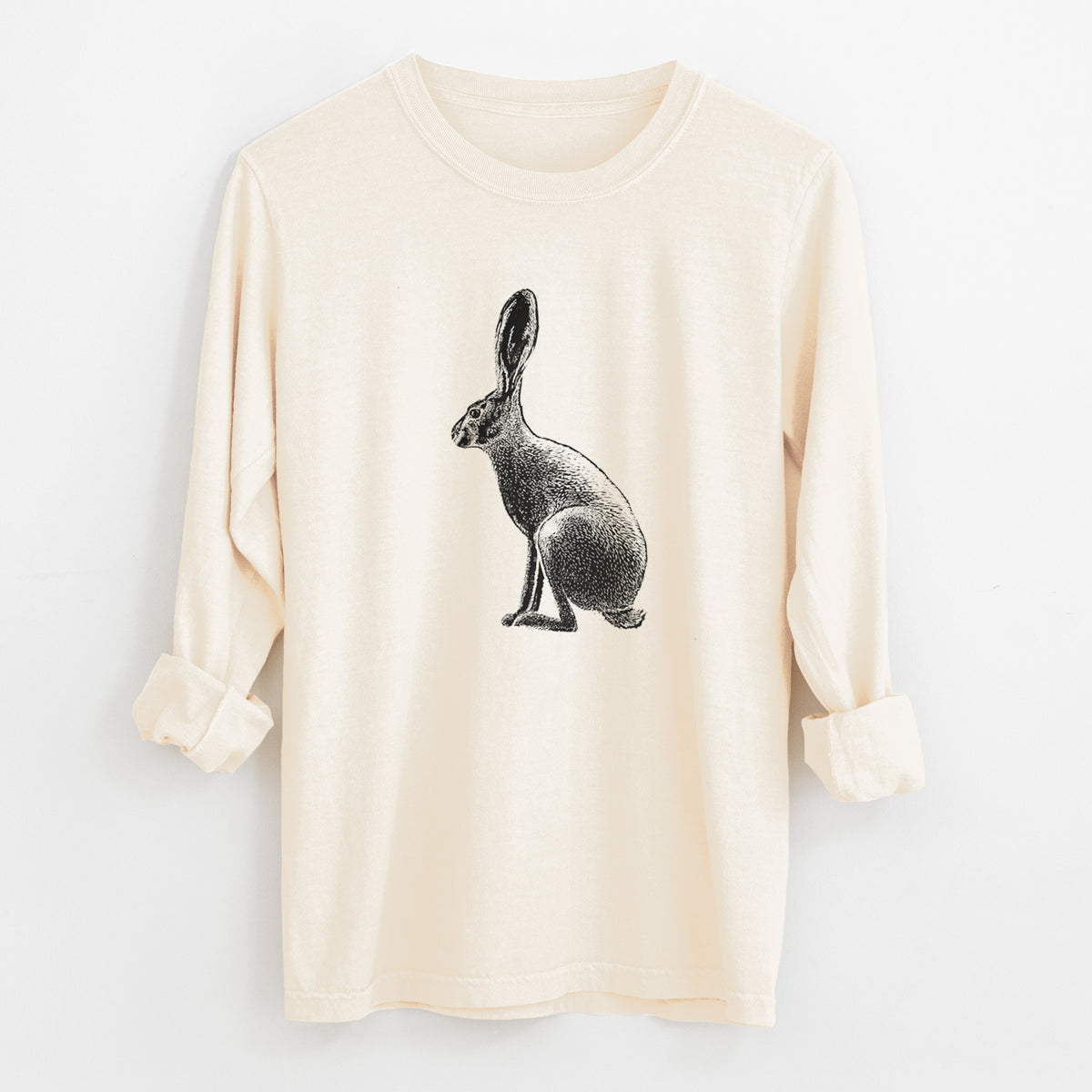 Ivory Comfort Colors long sleeve shirt laid flat with the cuffs rolled, printed with a detailed black ink illustration of a black-tailed jackrabbit sitting in profile with tall ears.