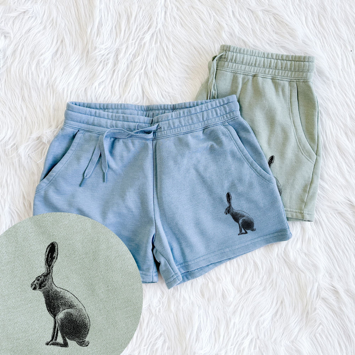 Two pairs of Cali Wave shorts in different colors printed with a detailed black ink illustration of a black-tailed jackrabbit sitting in profile with tall ears, with a close-up of the print.
