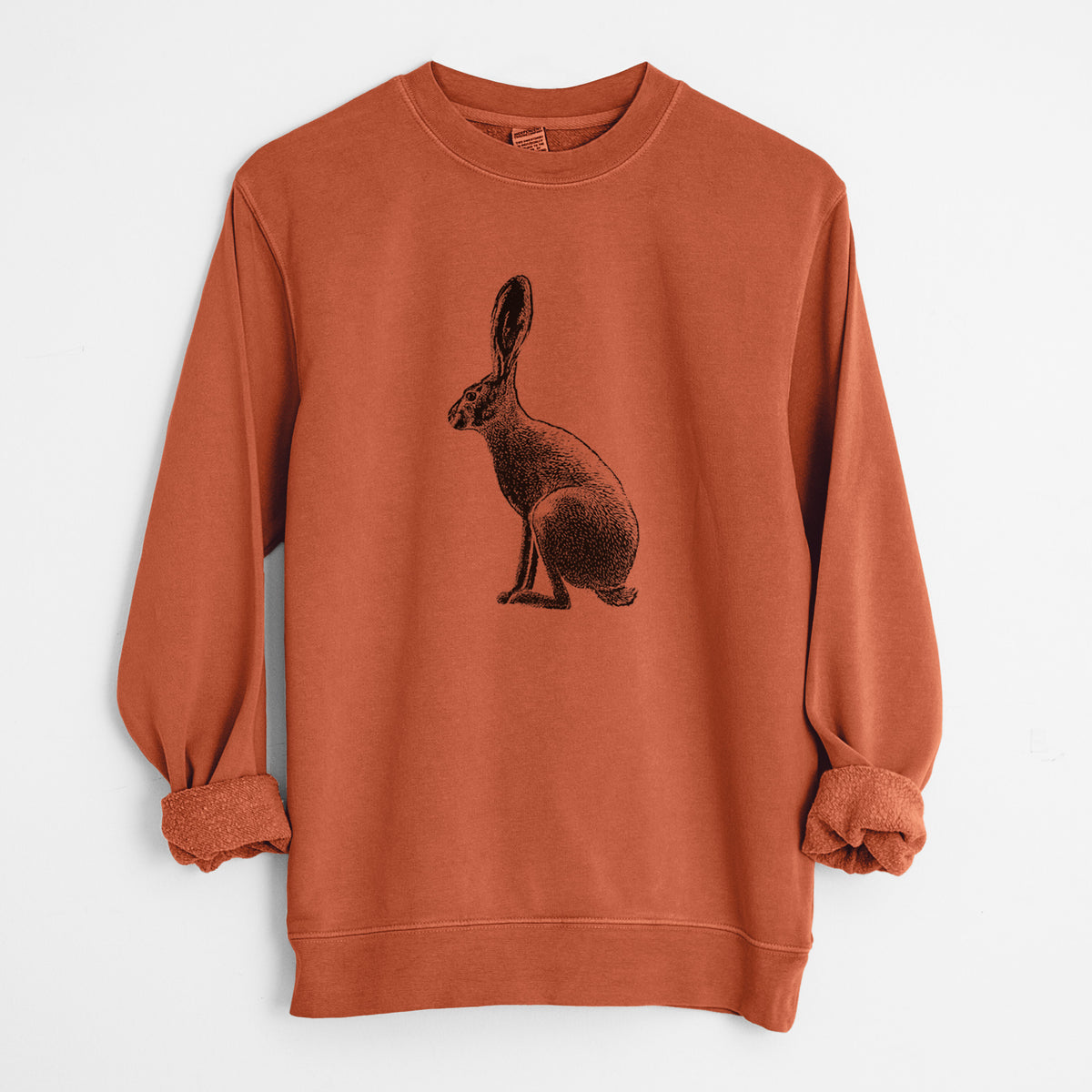 Amber orange pigment dyed crewneck sweatshirt laid flat with the sleeves rolled, printed with a detailed black ink illustration of a black-tailed jackrabbit sitting in profile with tall ears.