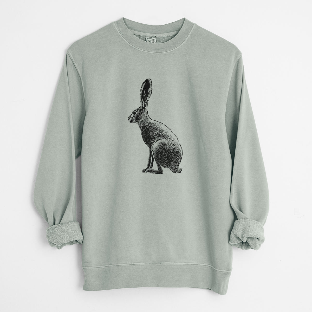 Sage green pigment dyed crewneck sweatshirt laid flat with the sleeves rolled, printed with a detailed black ink illustration of a black-tailed jackrabbit sitting in profile with tall ears.
