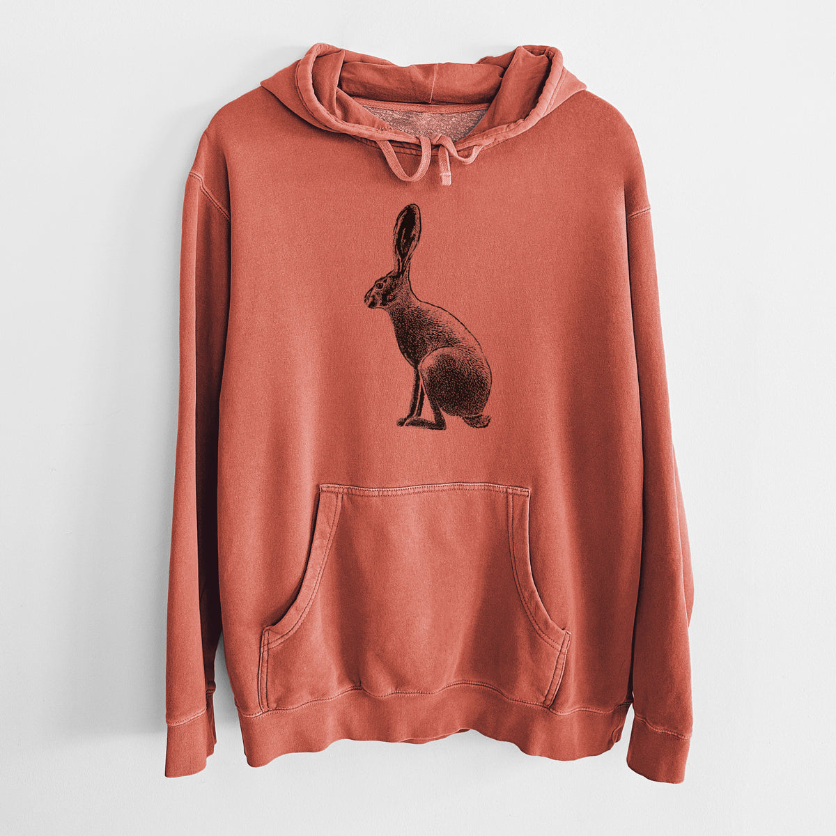 Amber orange pigment dyed hoodie laid flat, printed with a detailed black ink illustration of a black-tailed jackrabbit sitting in profile with tall ears.
