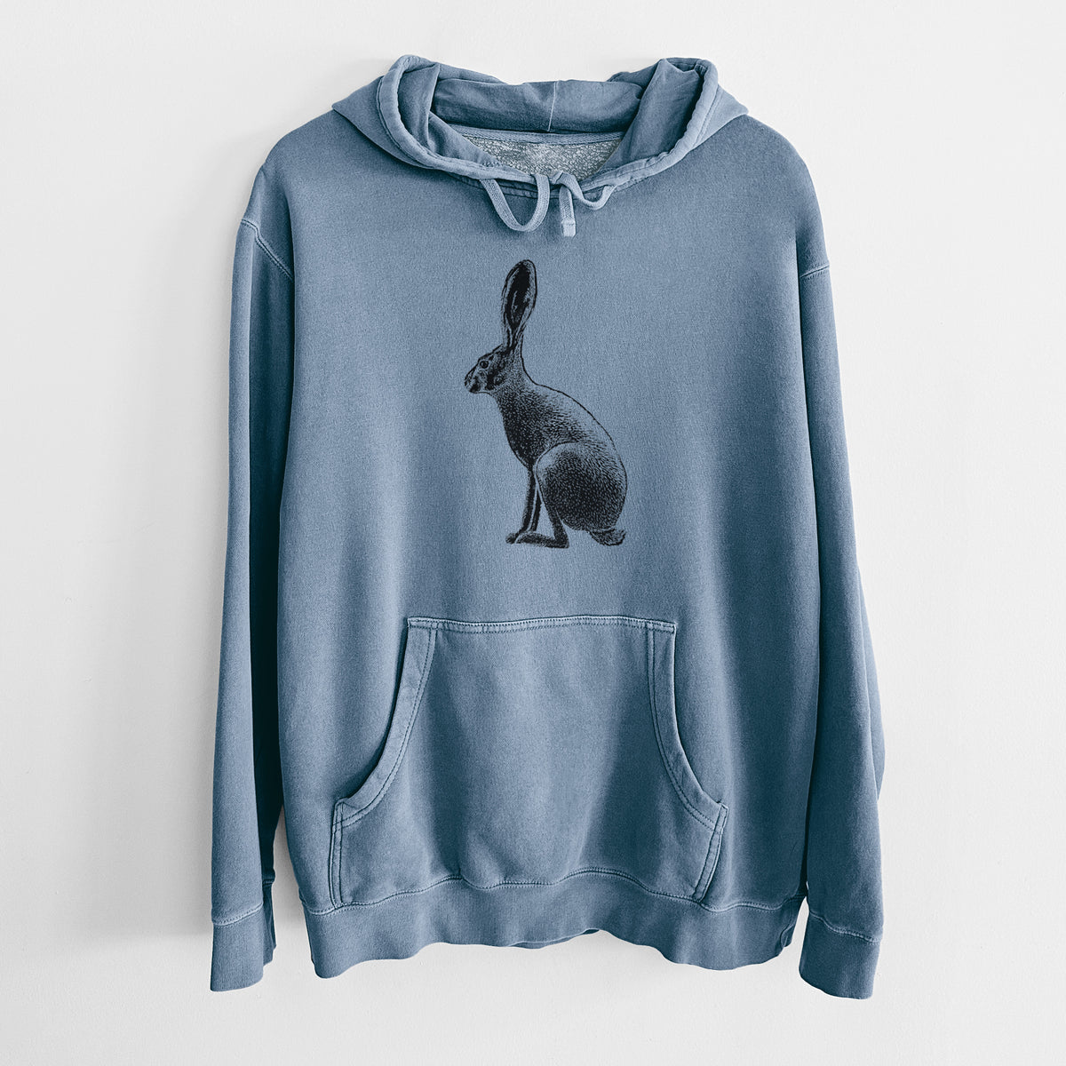 Slate blue pigment dyed hoodie laid flat, printed with a detailed black ink illustration of a black-tailed jackrabbit sitting in profile with tall ears.