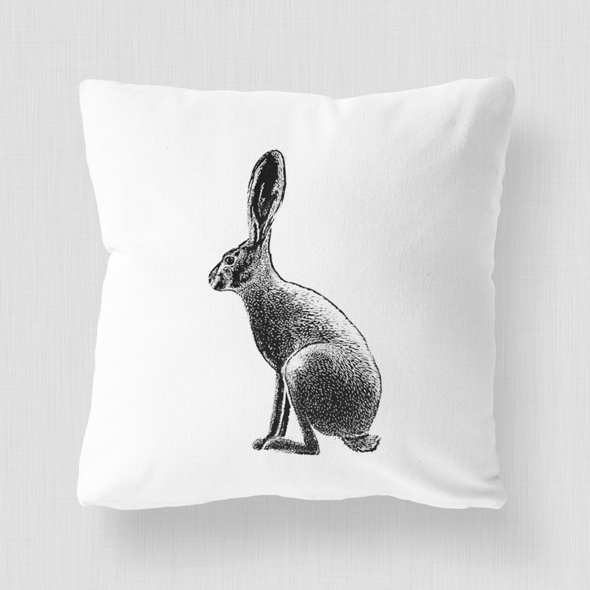 White pillow cover printed with a detailed black ink illustration of a black-tailed jackrabbit sitting in profile with tall ears.
