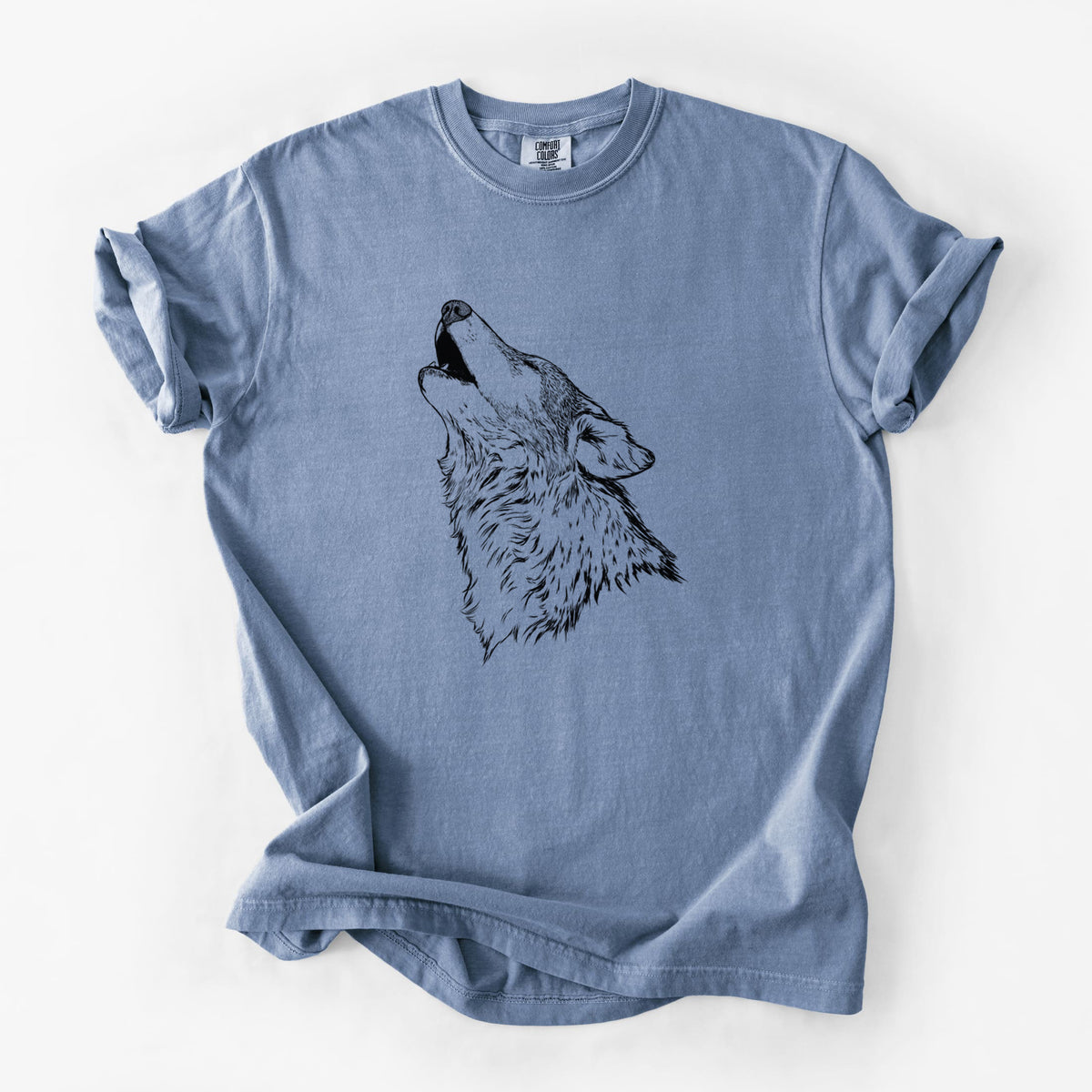 Blue jean Comfort Colors t-shirt laid flat, printed with a detailed black ink illustration of a grey wolf's head and shoulders, howling upward.