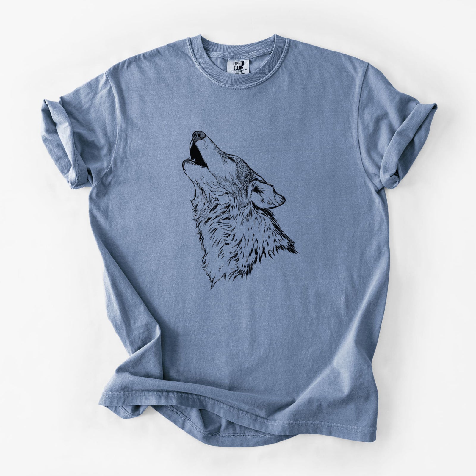 Blue jean Comfort Colors t-shirt laid flat, printed with a detailed black ink illustration of a grey wolf's head and shoulders, howling upward.