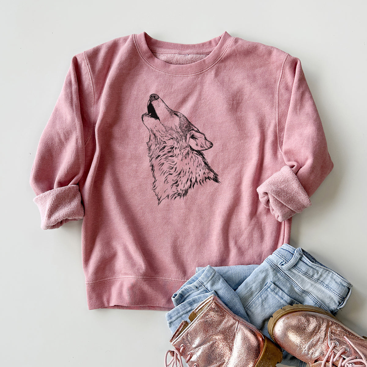 Youth crewneck sweatshirt printed with a detailed black ink illustration of a grey wolf's head and shoulders, howling upward, styled flat with jeans and boots.