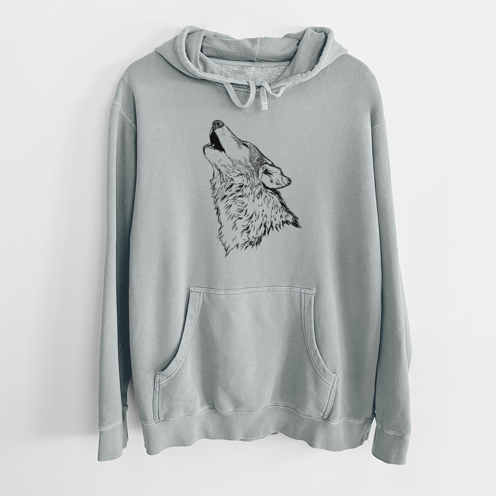 Sage green pigment dyed hoodie laid flat, printed with a detailed black ink illustration of a grey wolf's head and shoulders, howling upward.
