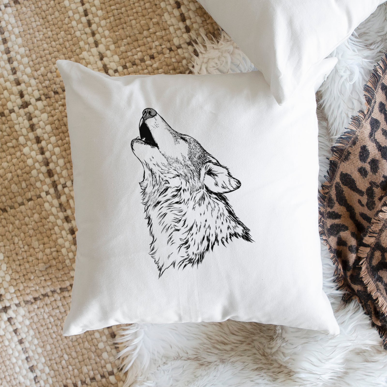 White pillow cover printed with a detailed black ink illustration of a grey wolf's head and shoulders, howling upward, on a bench beside plants.