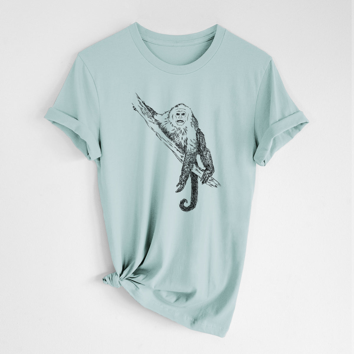 Dusty blue lightweight cotton t-shirt laid flat with the sleeves rolled, printed with a detailed black ink illustration of a capuchin monkey climbing a branch.