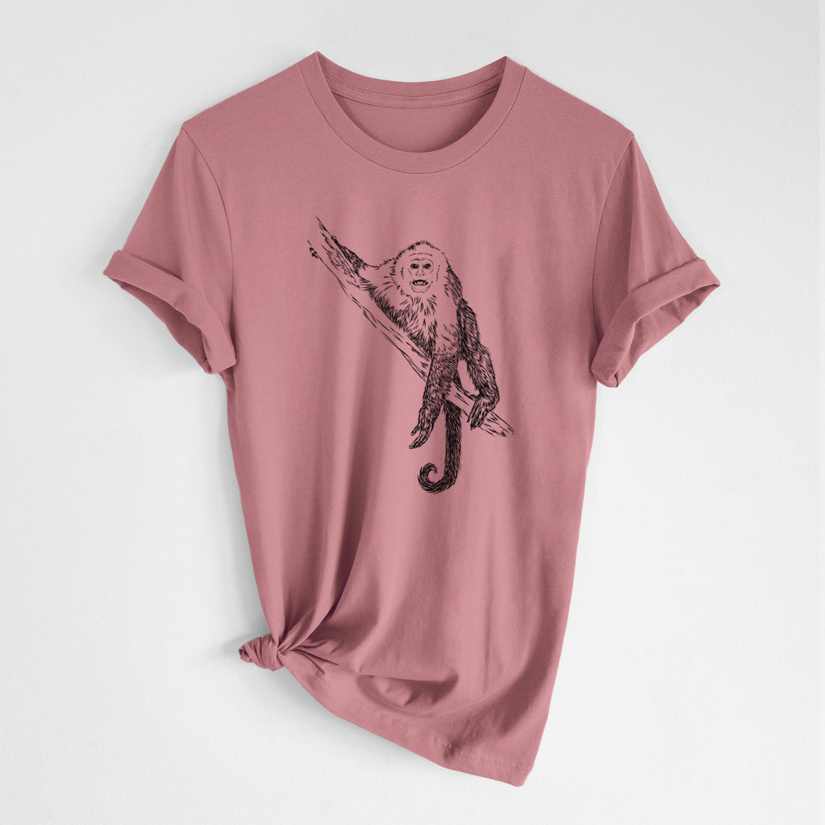 Mauve pink lightweight cotton t-shirt laid flat with the sleeves rolled, printed with a detailed black ink illustration of a capuchin monkey climbing a branch.