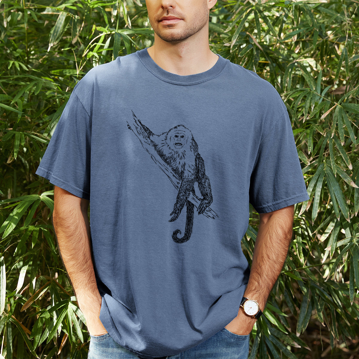 Man wearing a Comfort Colors t-shirt printed with a detailed black ink illustration of a capuchin monkey climbing a branch, outdoors.