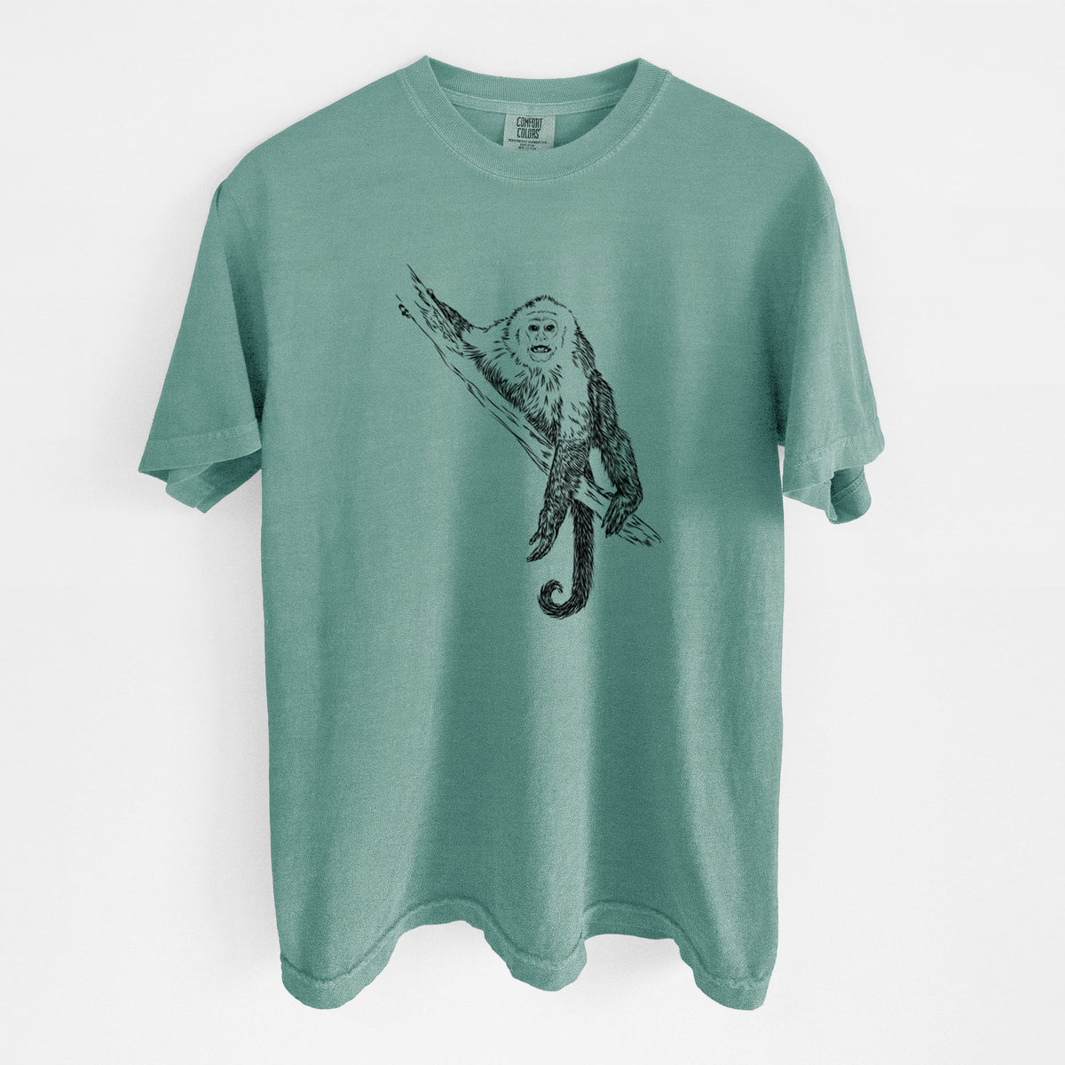 Reef green Comfort Colors t-shirt laid flat, printed with a detailed black ink illustration of a capuchin monkey climbing a branch.