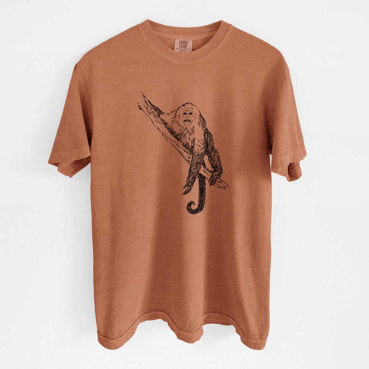 Yam burnt orange Comfort Colors t-shirt laid flat, printed with a detailed black ink illustration of a capuchin monkey climbing a branch.