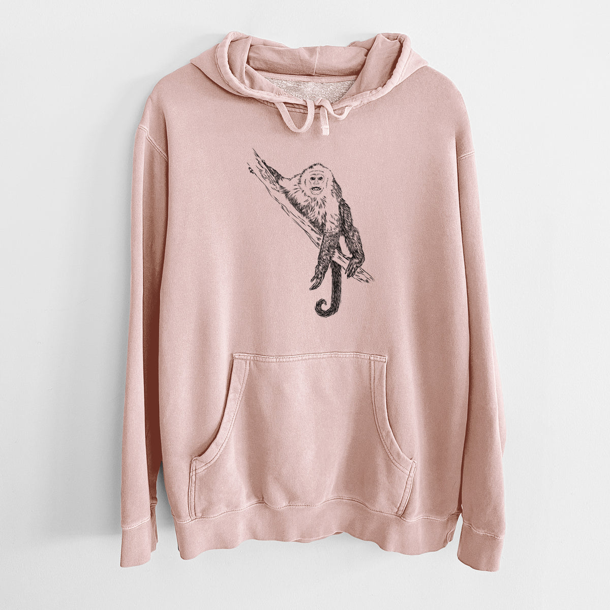 Dusty pink pigment dyed hoodie laid flat, printed with a detailed black ink illustration of a capuchin monkey climbing a branch.