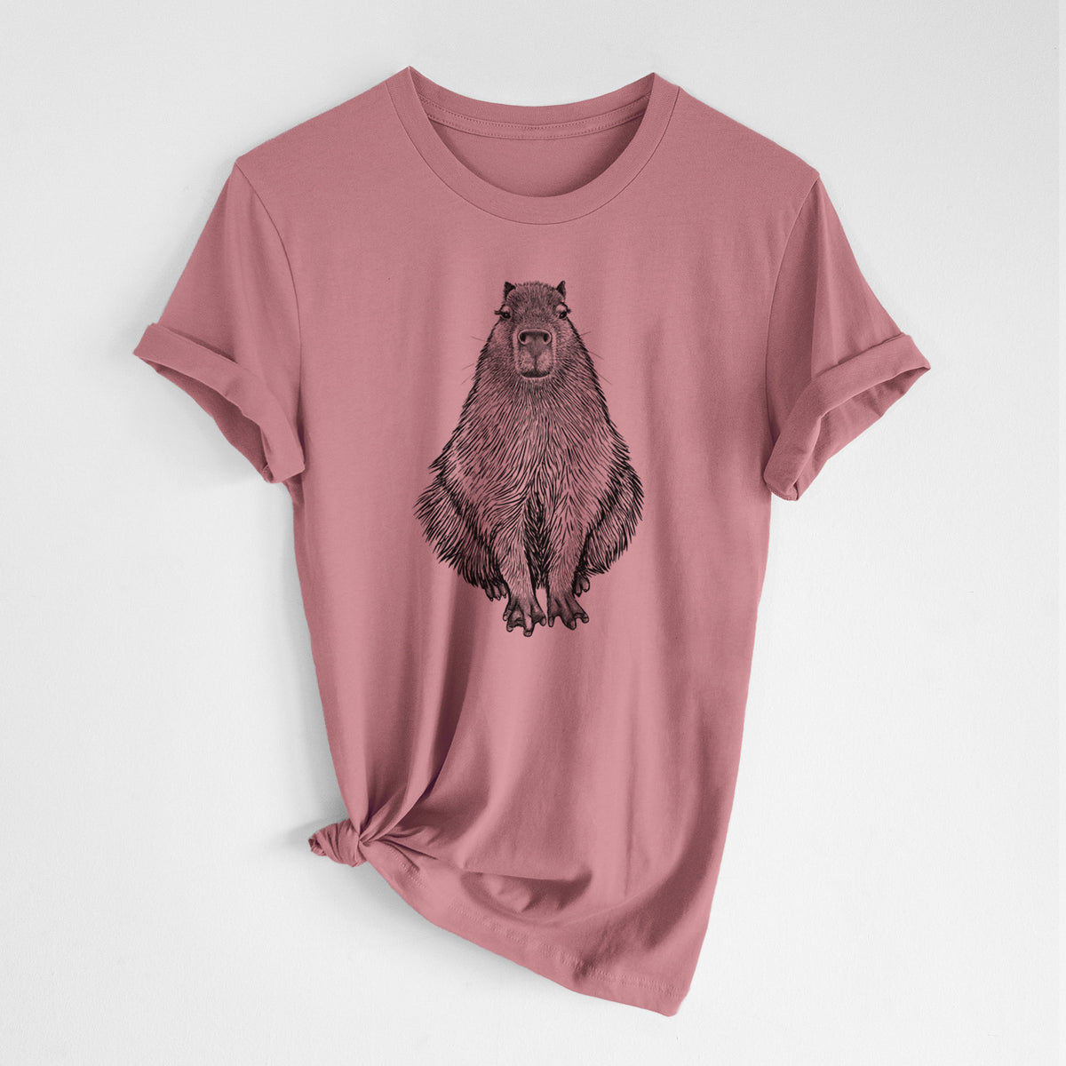 Mauve pink lightweight cotton t-shirt laid flat with the sleeves rolled, printed with a detailed black ink illustration of a capybara sitting and facing forward.