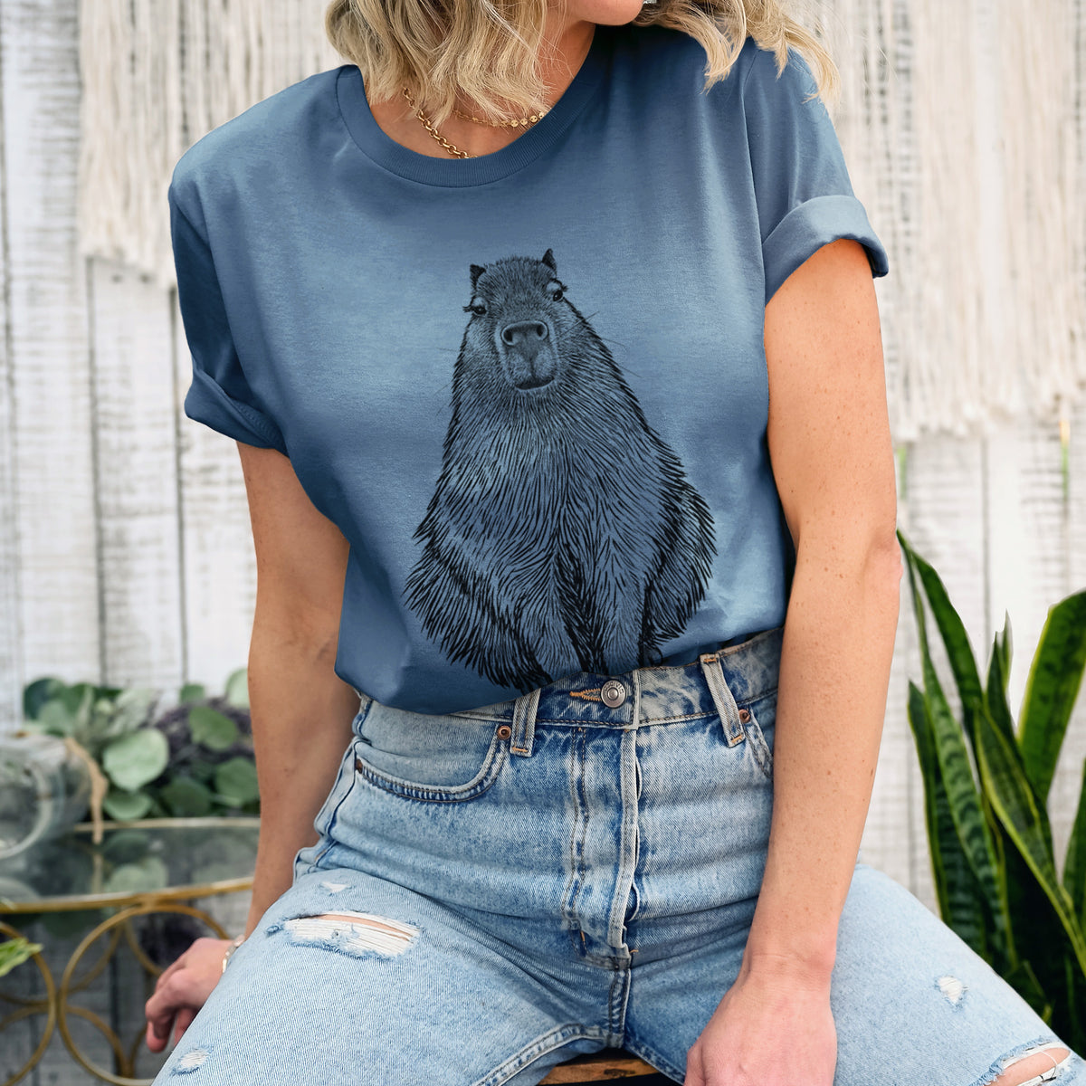 Woman wearing a steel blue lightweight cotton t-shirt printed with a detailed black ink illustration of a capybara sitting and facing forward.
