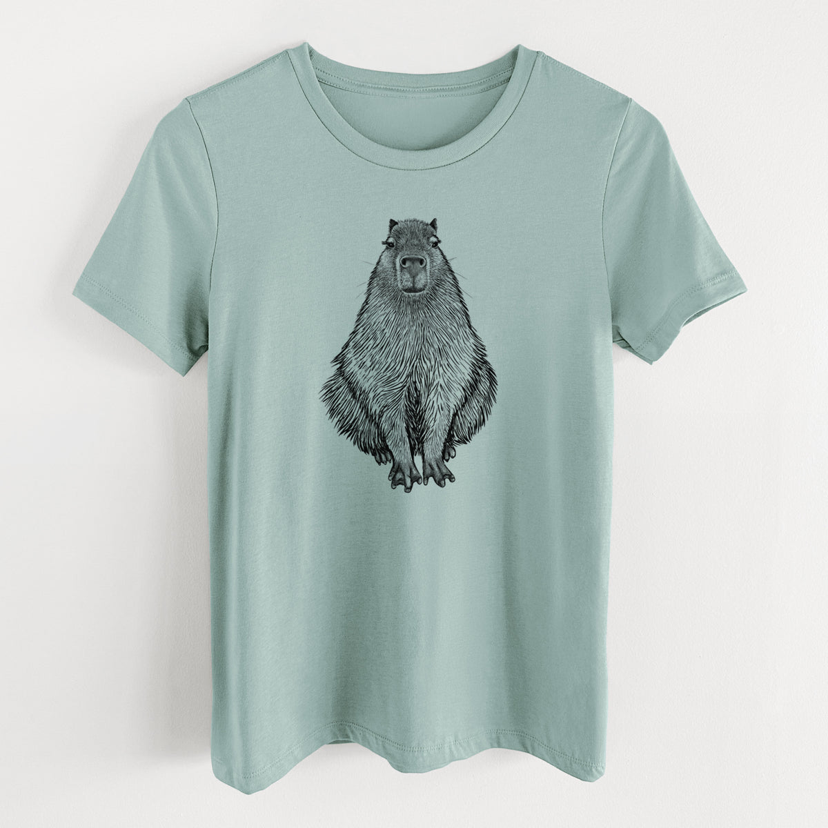 Dusty blue women's relaxed fit cotton t-shirt laid flat, printed with a detailed black ink illustration of a capybara sitting and facing forward.