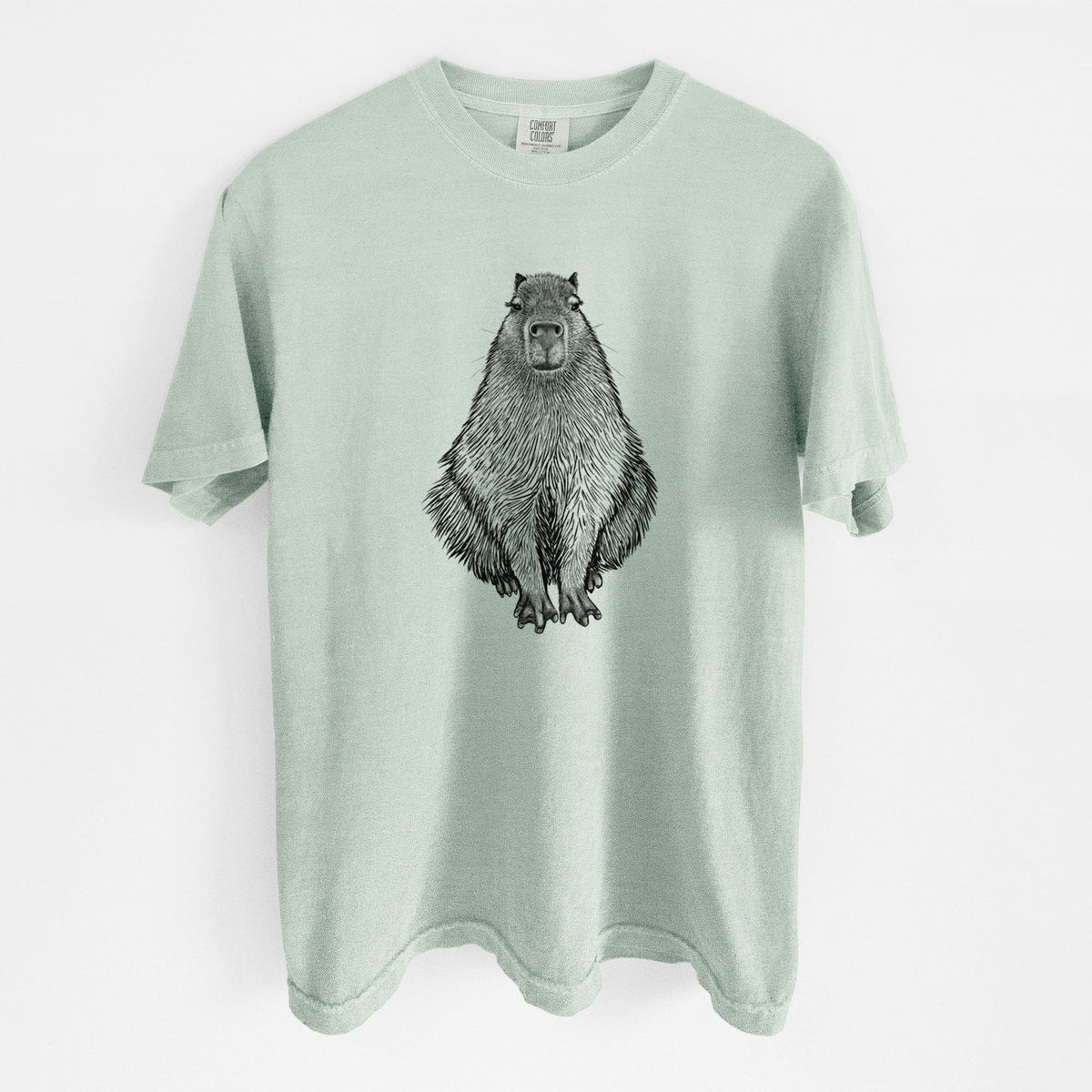 Bay green Comfort Colors t-shirt laid flat, printed with a detailed black ink illustration of a capybara sitting and facing forward.