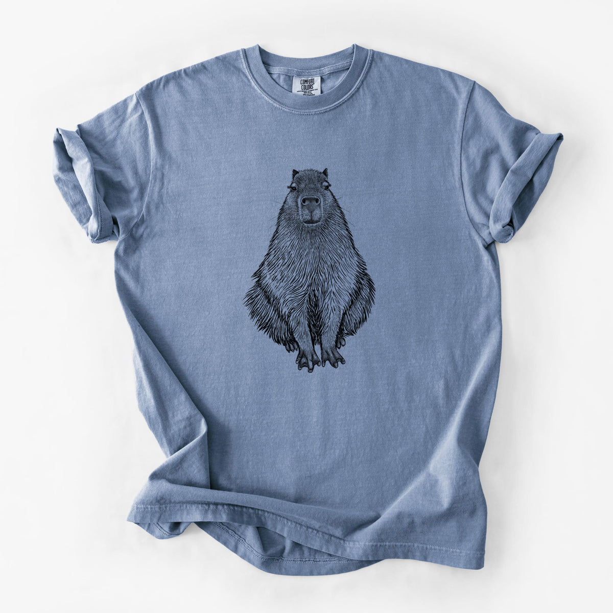 Blue jean Comfort Colors t-shirt laid flat, printed with a detailed black ink illustration of a capybara sitting and facing forward.