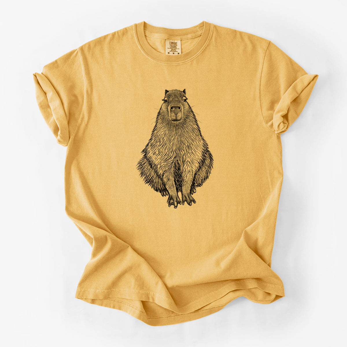 Golden wheat yellow Comfort Colors t-shirt laid flat, printed with a detailed black ink illustration of a capybara sitting and facing forward.