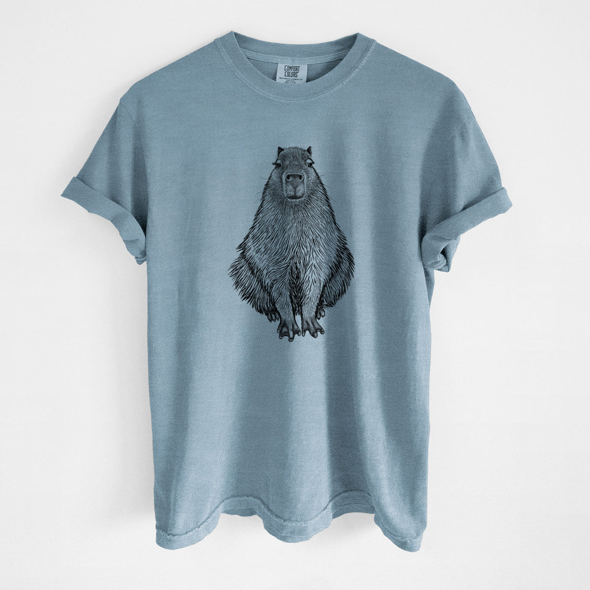 Steel blue Comfort Colors t-shirt laid flat, printed with a detailed black ink illustration of a capybara sitting and facing forward.