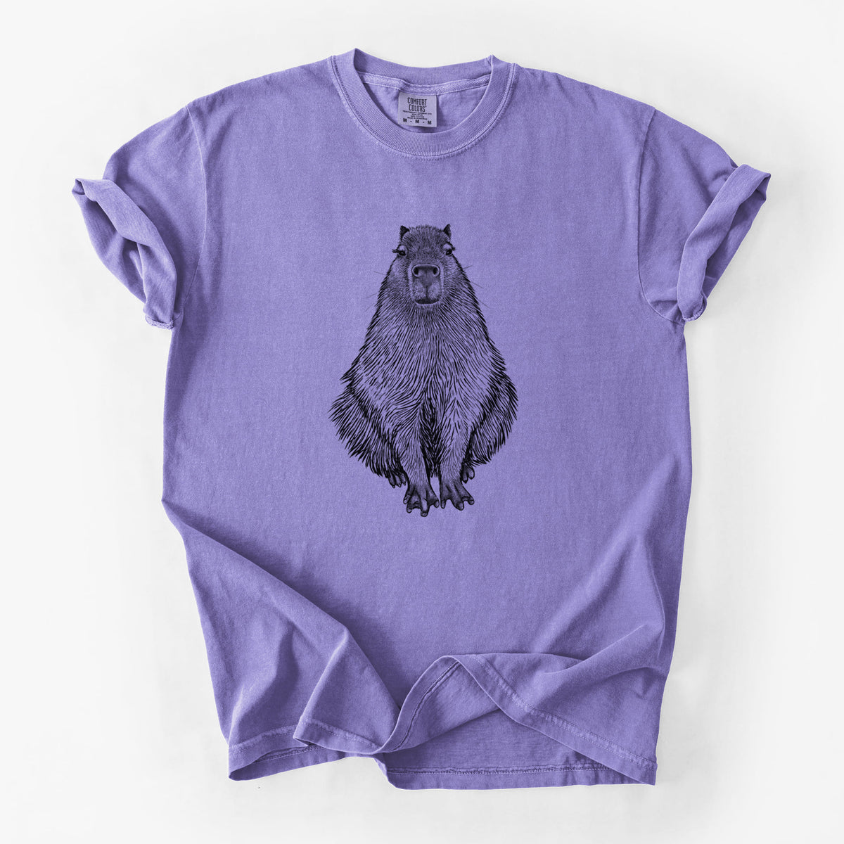 Violet purple Comfort Colors t-shirt laid flat, printed with a detailed black ink illustration of a capybara sitting and facing forward.