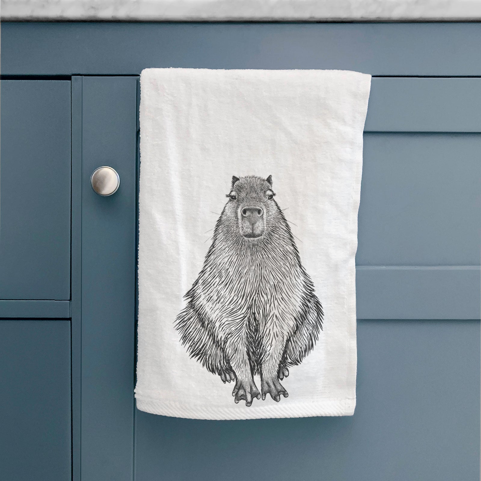 White hand towel printed with a detailed black ink illustration of a capybara sitting and facing forward.