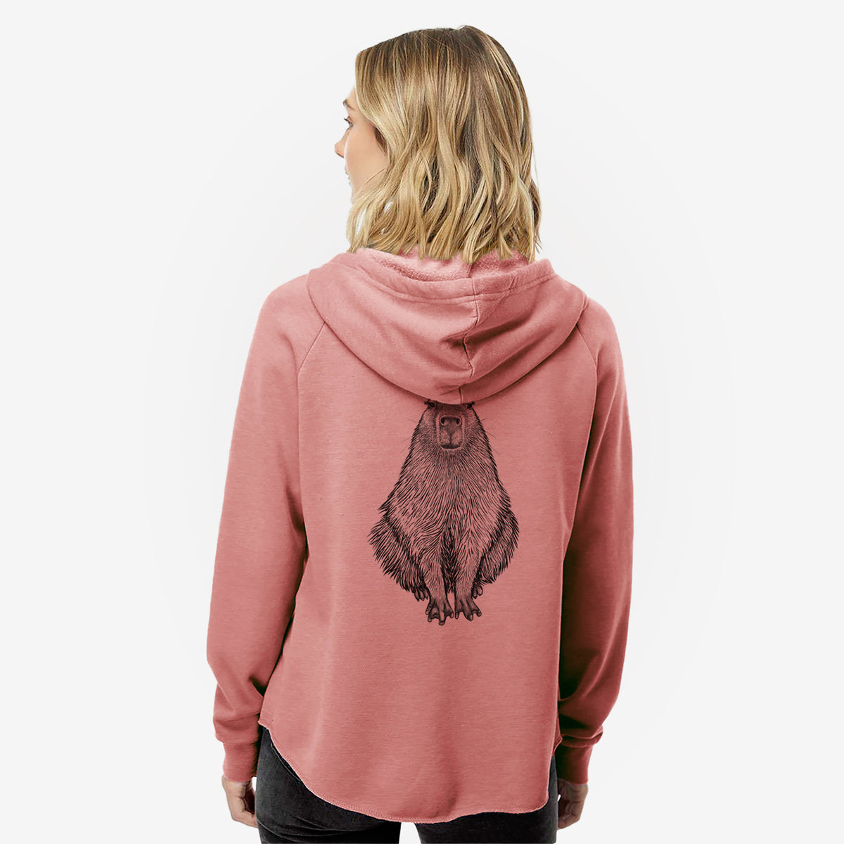 Woman wearing a dusty rose women's Cali Wave zip-up sweatshirt printed with a detailed black ink illustration of a capybara sitting and facing forward, seen from behind.