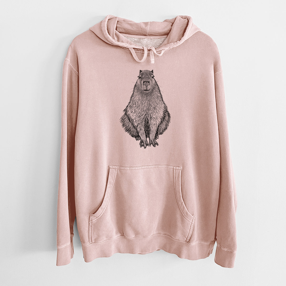 Dusty pink pigment dyed hoodie laid flat, printed with a detailed black ink illustration of a capybara sitting and facing forward.