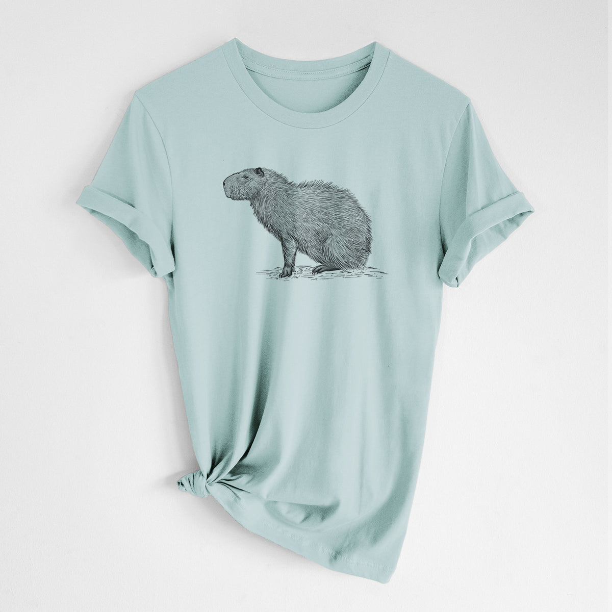 Dusty blue lightweight cotton t-shirt laid flat with the sleeves rolled, printed with a detailed black ink illustration of a capybara standing in profile.