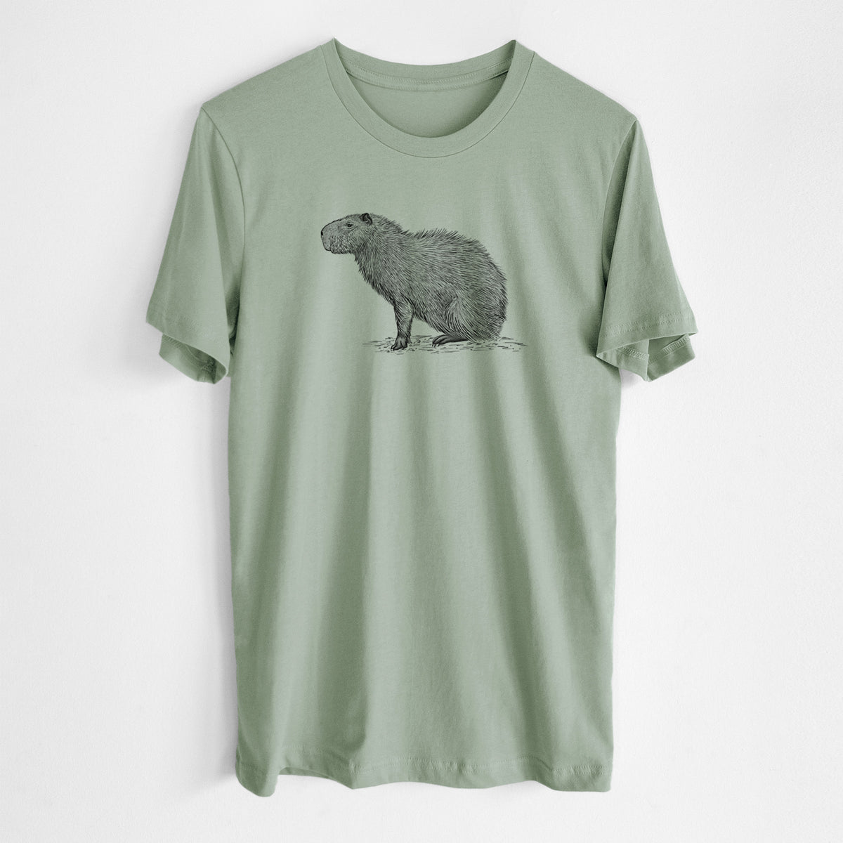 Sage green lightweight cotton t-shirt laid flat, printed with a detailed black ink illustration of a capybara standing in profile.