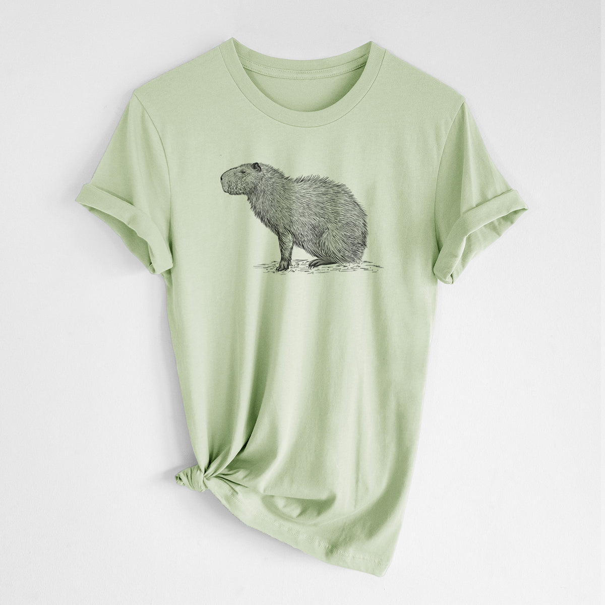 Spring green lightweight cotton t-shirt laid flat with the sleeves rolled, printed with a detailed black ink illustration of a capybara standing in profile.