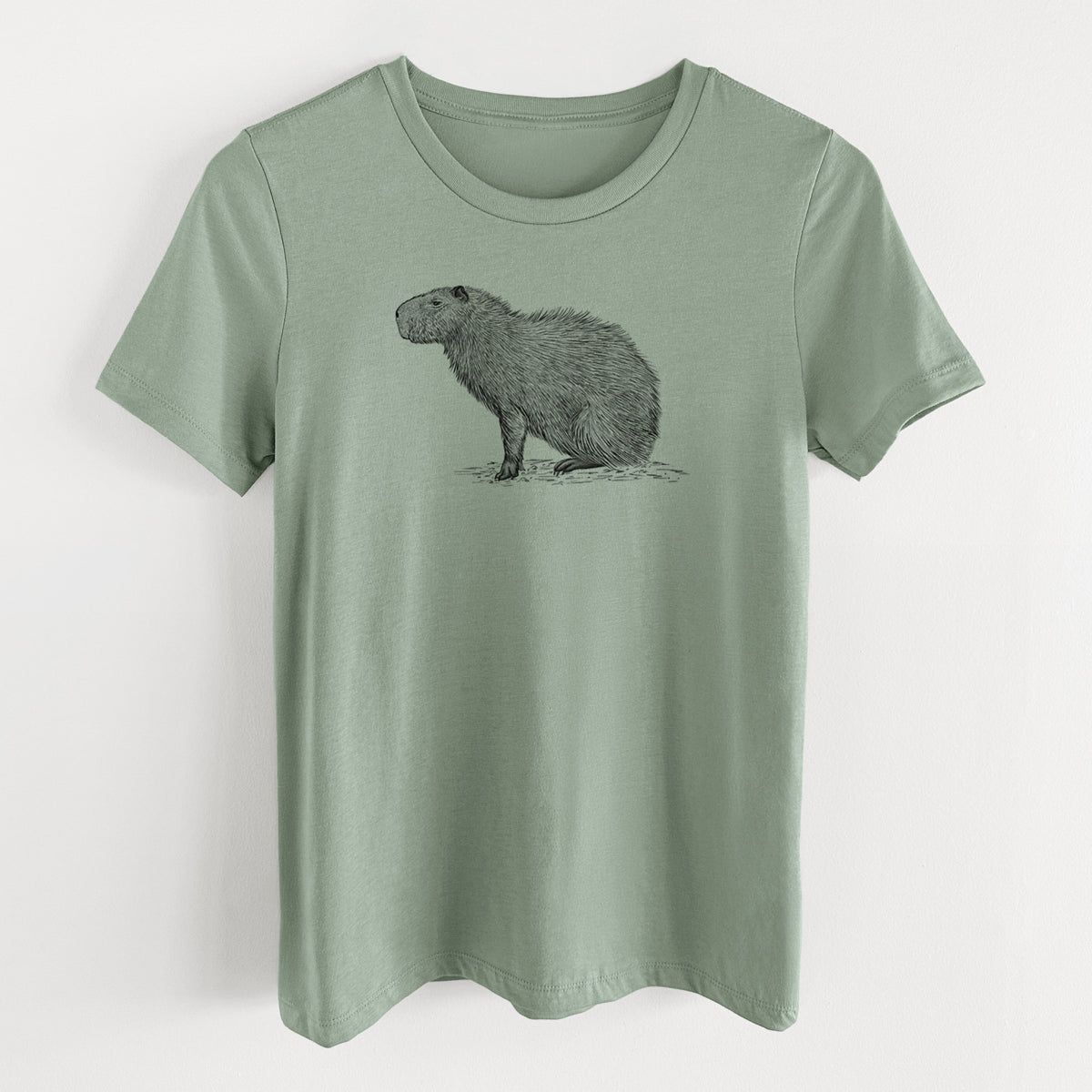Sage green women's relaxed fit cotton t-shirt laid flat, printed with a detailed black ink illustration of a capybara standing in profile.