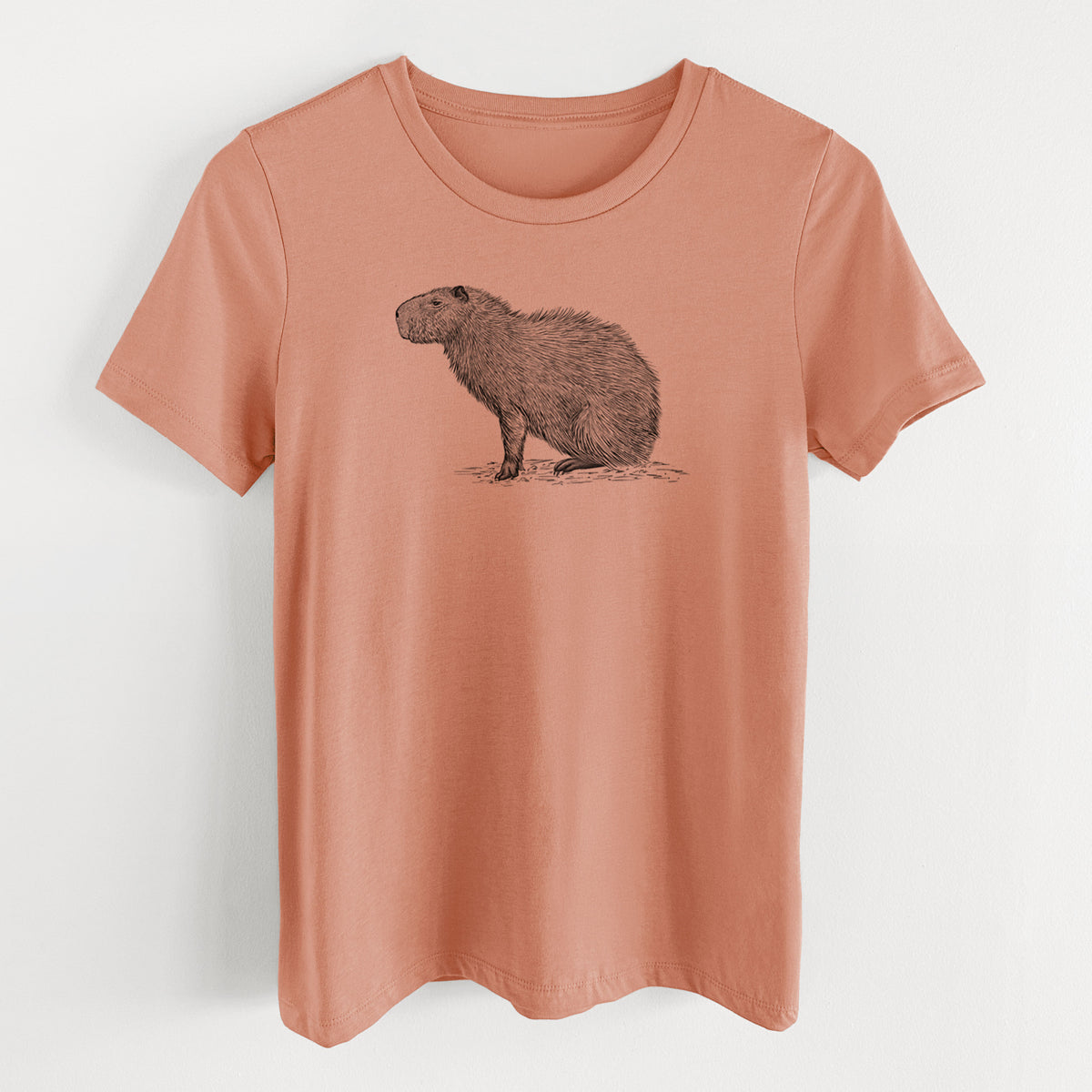 Terracotta orange women's relaxed fit cotton t-shirt laid flat, printed with a detailed black ink illustration of a capybara standing in profile.