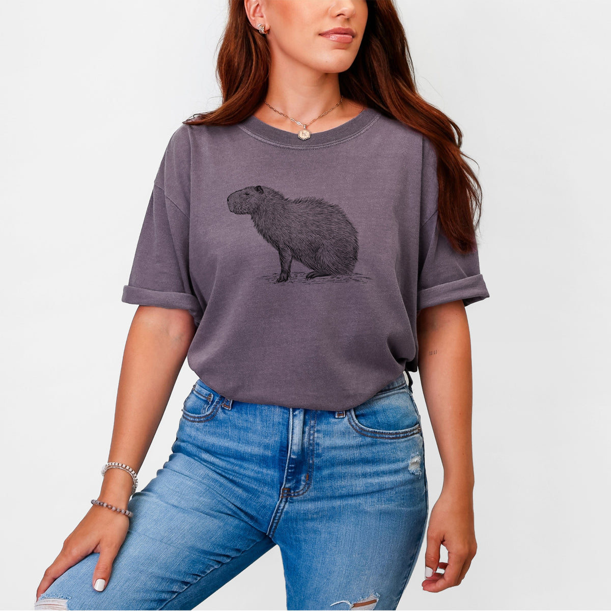 Woman wearing a Comfort Colors t-shirt printed with a detailed black ink illustration of a capybara standing in profile.
