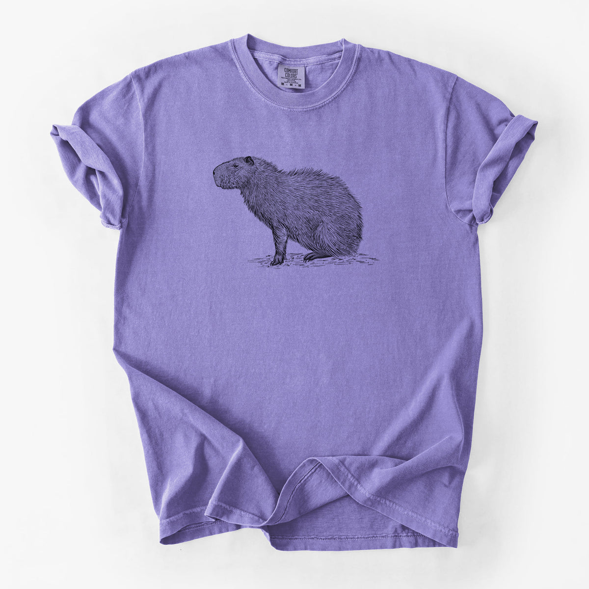 Violet purple Comfort Colors t-shirt laid flat, printed with a detailed black ink illustration of a capybara standing in profile.