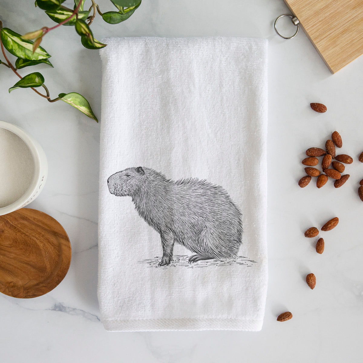 White hand towel printed with a detailed black ink illustration of a capybara standing in profile.