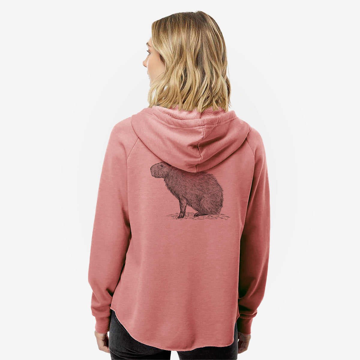 Woman wearing a dusty rose women's Cali Wave zip-up sweatshirt printed with a detailed black ink illustration of a capybara standing in profile, seen from behind.