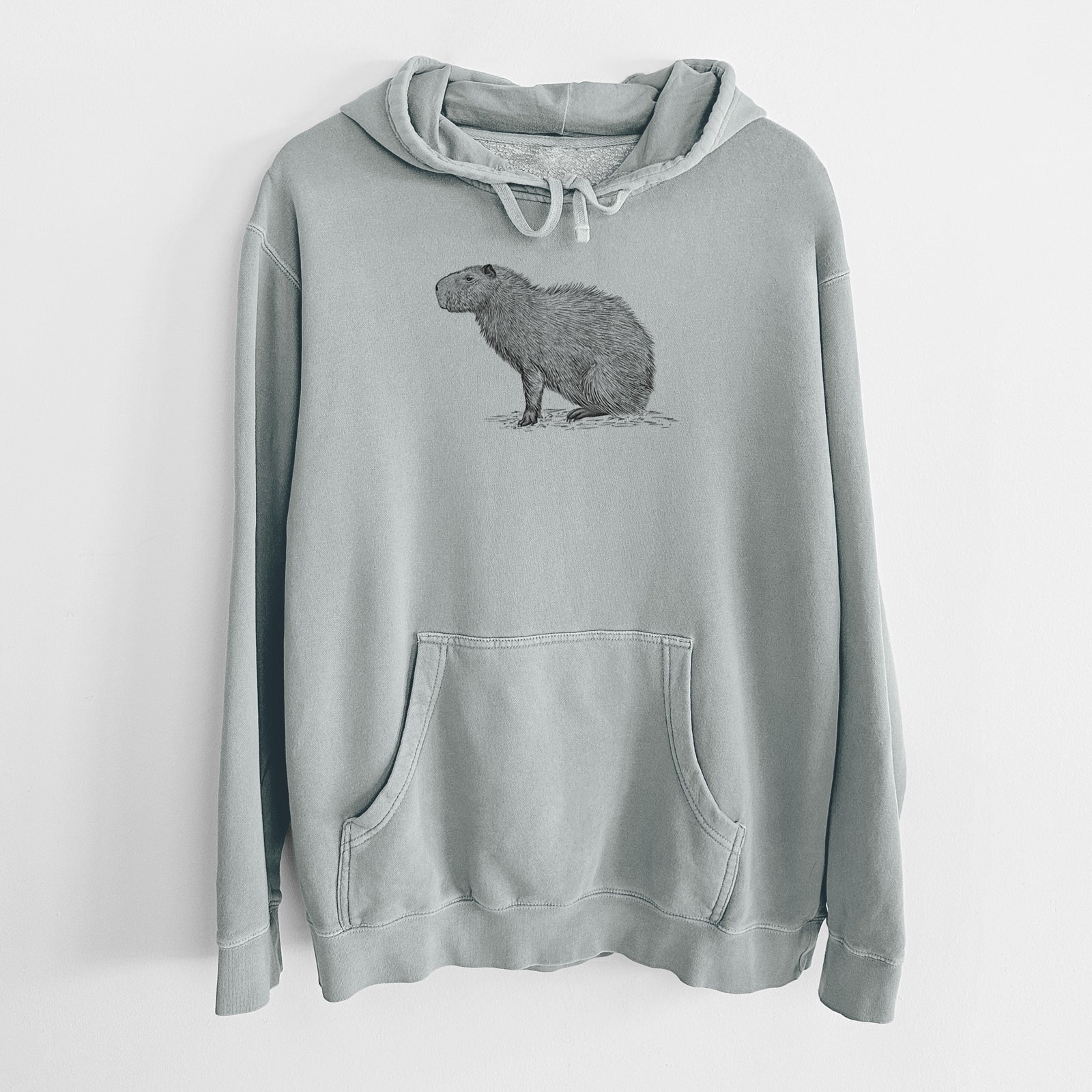 Sage green pigment dyed hoodie laid flat, printed with a detailed black ink illustration of a capybara standing in profile.