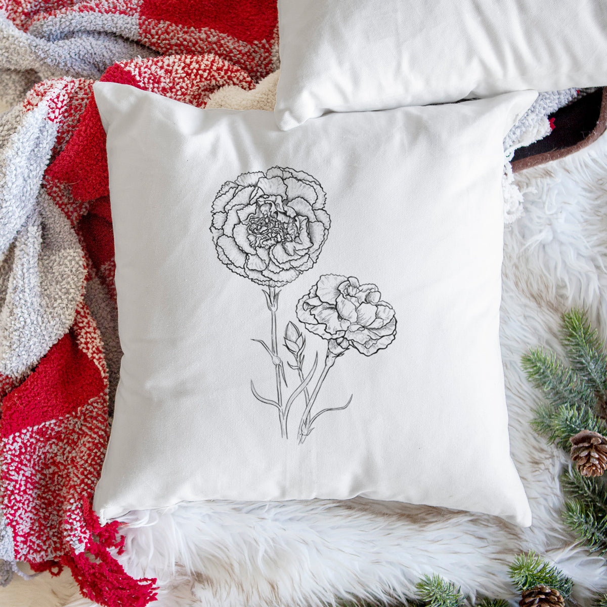 White pillow cover printed with a black ink line drawing of carnation flowers on stems, on a woven chair.
