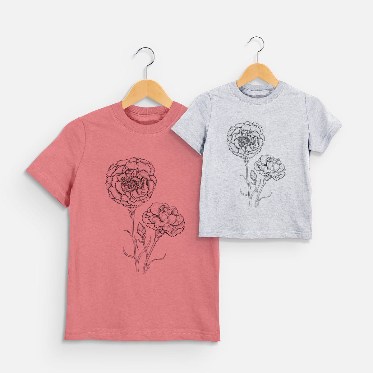 Two youth t-shirts in different colors on hangers, printed with a black ink line drawing of carnation flowers on stems.