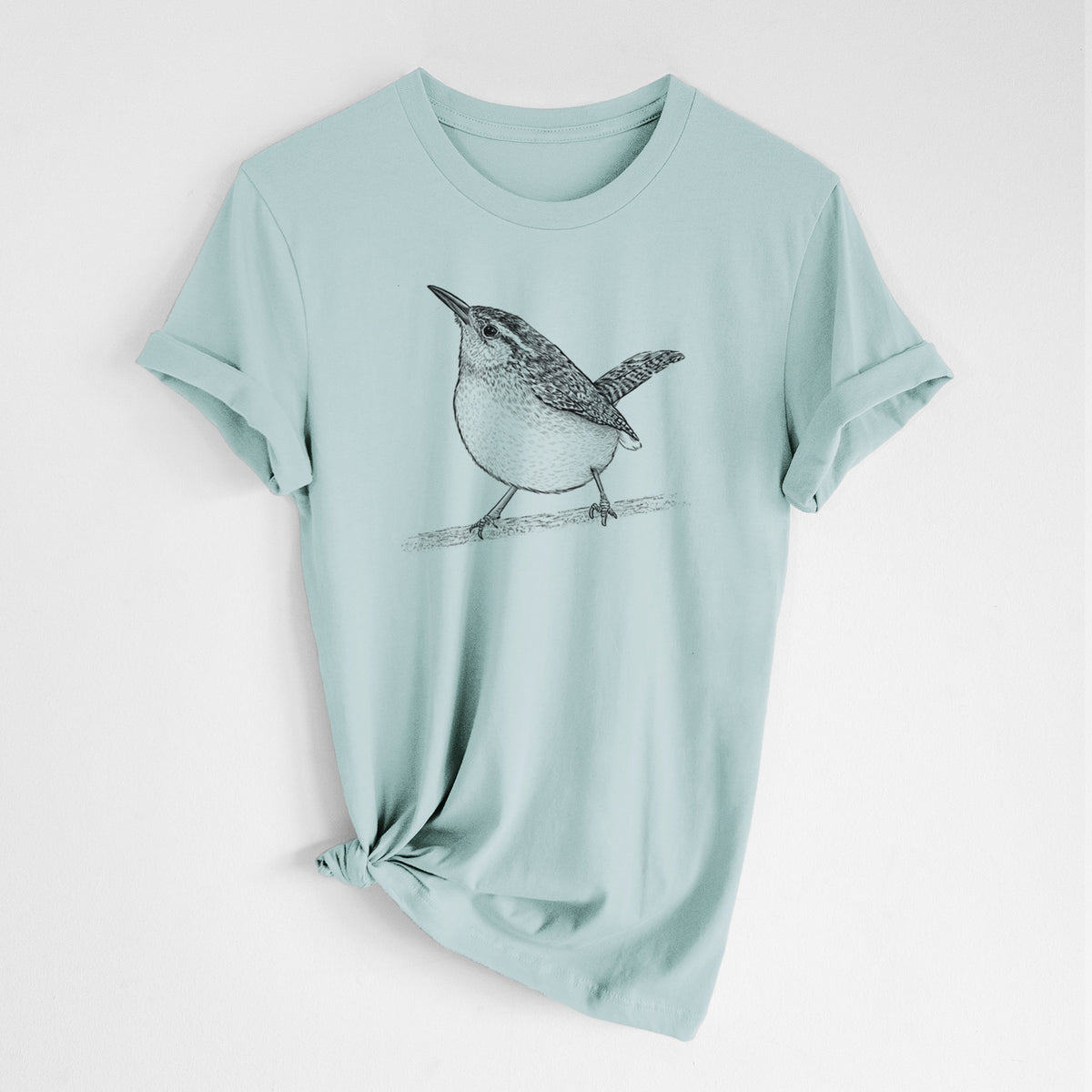 Dusty blue lightweight cotton t-shirt laid flat with the sleeves rolled, printed with a detailed black ink sketch of a Carolina wren perched on a branch with its tail raised.