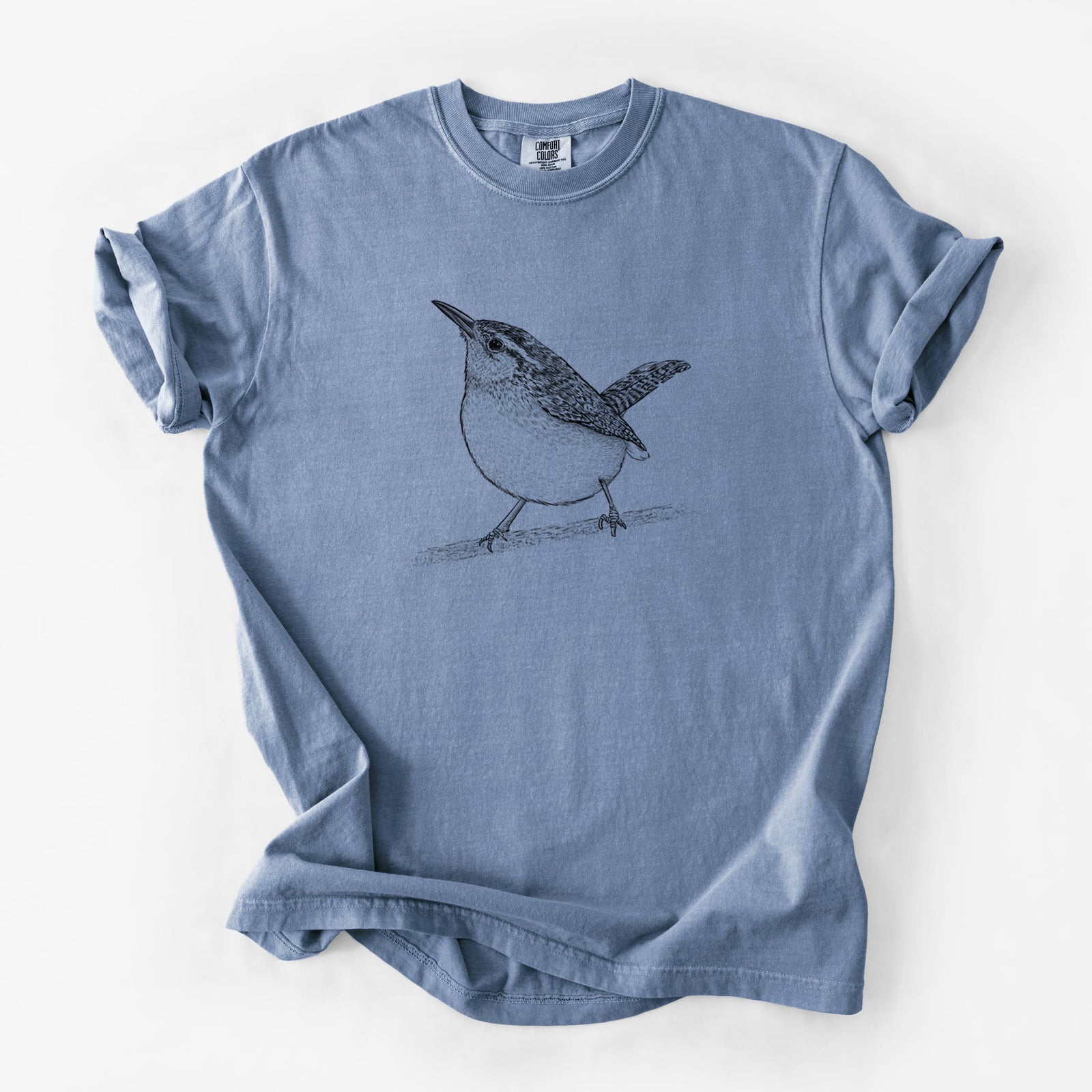 Blue jean Comfort Colors t-shirt laid flat, printed with a detailed black ink sketch of a Carolina wren perched on a branch with its tail raised.