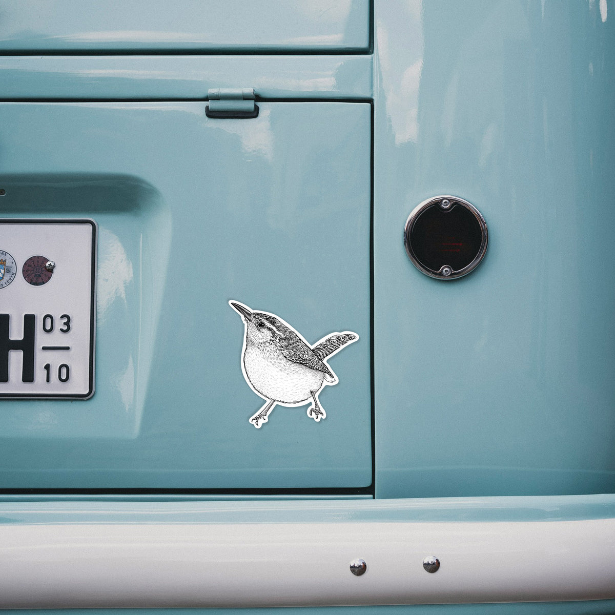 4 inch vinyl decal of a detailed black ink sketch of a Carolina wren perched on a branch with its tail raised on the back of a van.