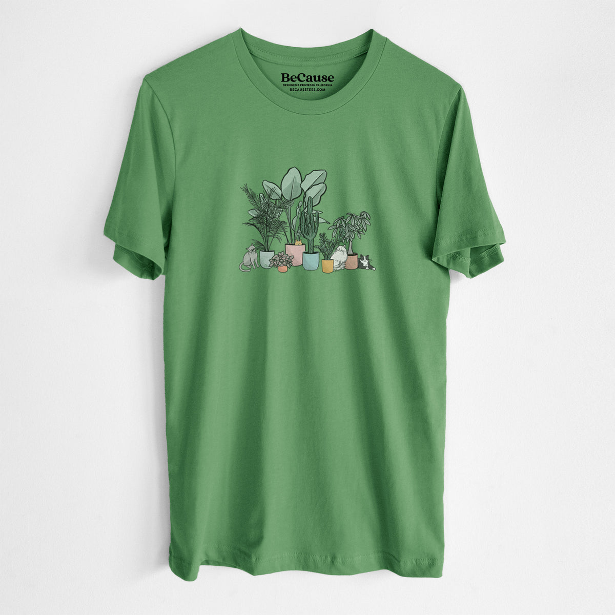 Leaf green lightweight cotton t-shirt laid flat, printed with a full-color illustration of cats lounging among potted houseplants.